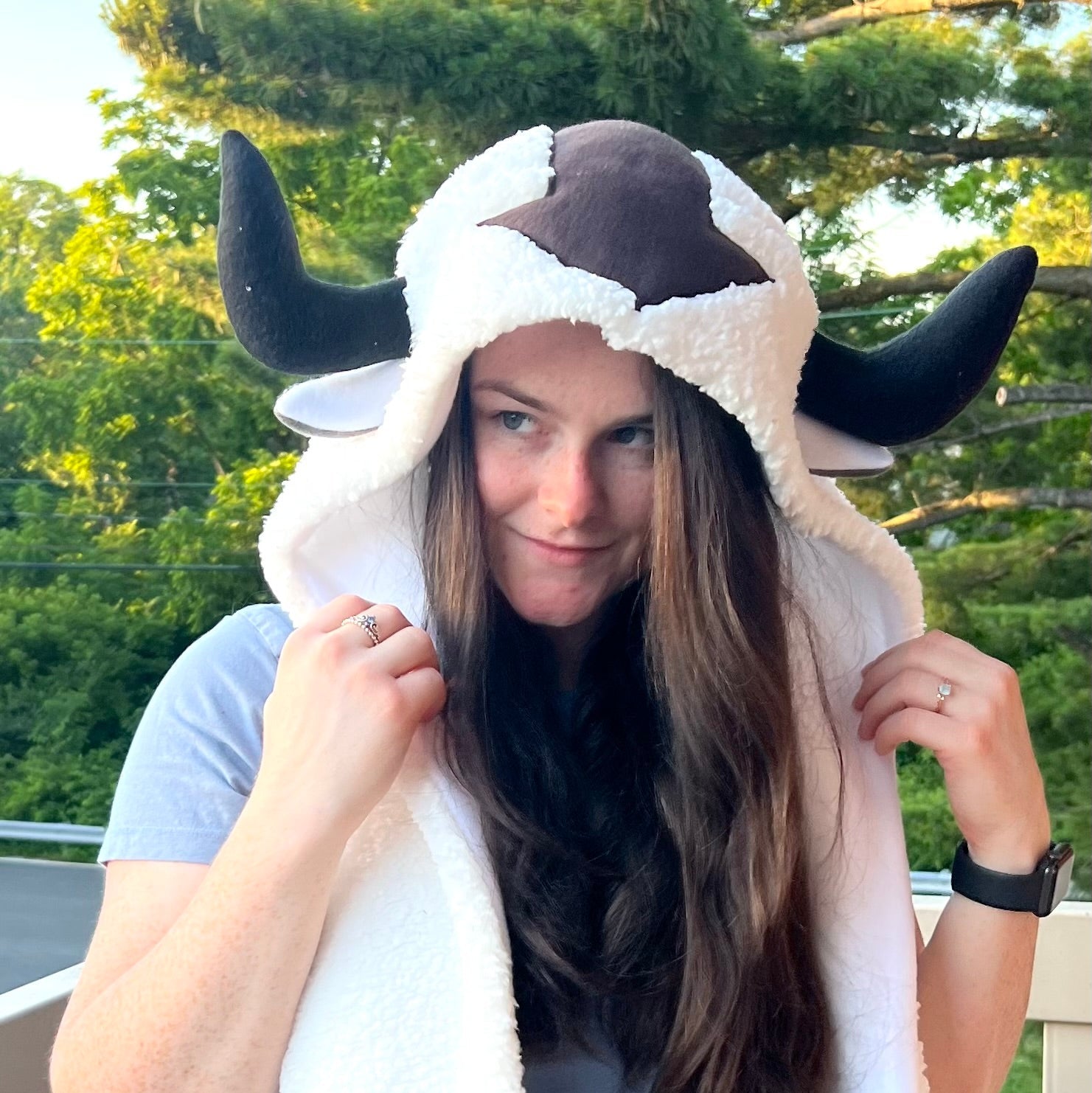 Person wearing a cow-themed hood with horns outdoors